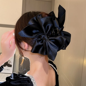 Grande pince à cheveux élégante avec nœud en satin noir portée sur un chignon chic
