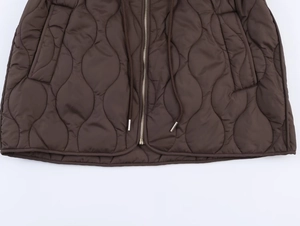 Détail macro d'une veste matelassée marron foncé montrant zip et cordons de serrage