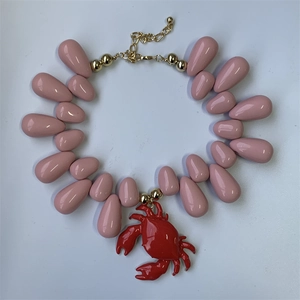 Detailed view of ocean style pink teardrop beads and red crab pendant necklace