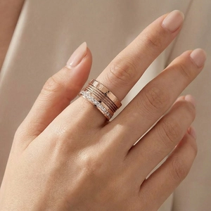 Detailed view of rose gold layered ring with roman numerals and twisted steel cable details
