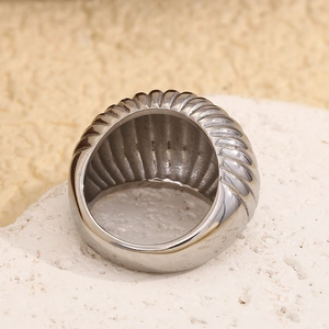 Vue macro de la bague large argentée avec texture plissée en spirale sur pierre blanche