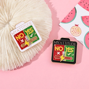 Detail of sliding 'MY ATTITUDE' enamel pins with 'YES' or 'NO' toggle on pink surface