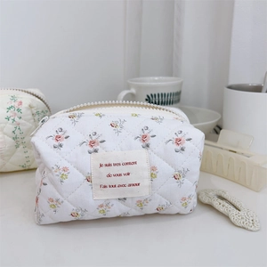 Détail d'une trousse à maquillage matelassée fleurie avec étiquette de texte français