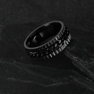 Schwarzer Edelstahlring im Industrial-Punk-Stil mit Kettenelement auf schwarzem Fels