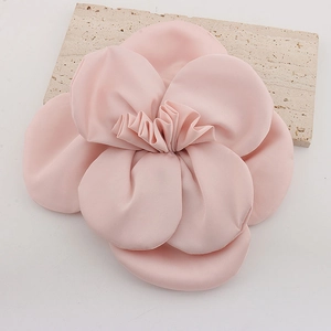 Detailed view of a handmade pink fabric rose brooch on a decorative stone base
