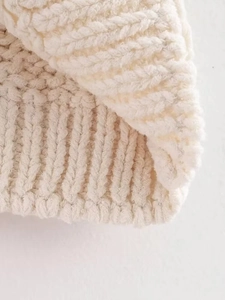 Close-up of white knit fabric texture and ribbed stitching details on asymmetric top