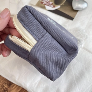 Close-up of gray-blue canvas makeup bag showing zipper detail and internal compartment