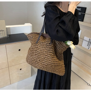 Detail of hand-woven straw tote bag with brown leather straps and spacious interior