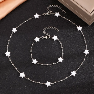 Détail de l'ensemble collier et bracelet argenté avec perles étoiles blanches sur fond noir
