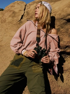 Detailed texture of pink half-zip fleece hoodie against a natural rock background