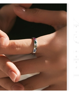Macro detail of silver heart ring featuring colorful gemstones and artistic light shadows