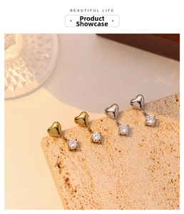 Close-up of heart tassel zircon earrings in gold and silver on a textured stone base