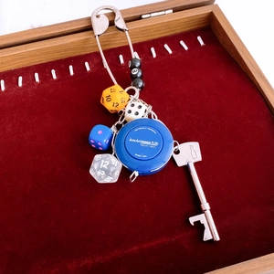 Detail of creative keychain with mini measuring tape, dice, and metal pin on velvet