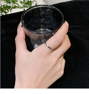 Detail of a sparkling faceted silver steel ring worn while holding a black glass