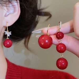 Detail shot of red resin beaded tassel earrings with gold plating and butterfly accents