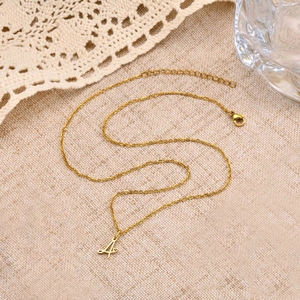 Close-up of golden stainless steel necklace with letter A pendant and heart detail