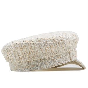 Close-up of beige tweed baker boy hat featuring textured weave and short brim detail