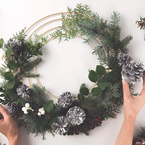 DIY Christmas wreath kit with gold metal rings, pine branches, and berries on white backdrop