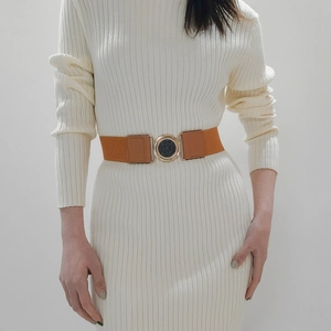 Brown elastic waist belt with gold round buckle worn on a beige dress for women