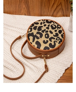 Detail of leopard print cylindrical handbag with gold hardware on white knit blanket