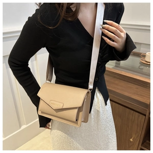 Close-up of beige crossbody square bag with wide fabric strap and fashion label detail