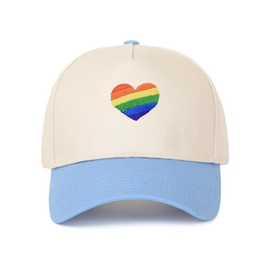 Dettaglio del ricamo a cuore arcobaleno su un cappellino da baseball bicolore alla moda