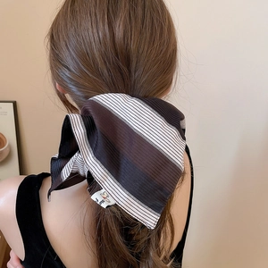 Close-up of a striped fabric scrunchie with silk-like texture tied on a ponytail