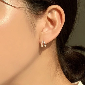 Macro side view of elegant gold U-shaped minimalist earrings on model ear