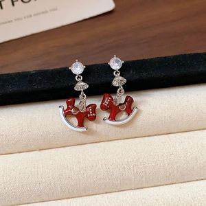 Close-up of red rocking horse earrings with 18k gold plating and white zircon inlay