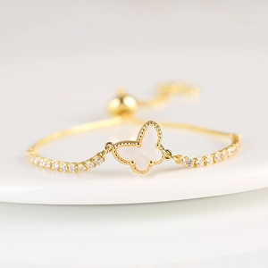 Macro shot of gold butterfly bracelet with white shell inlay and zircon accents