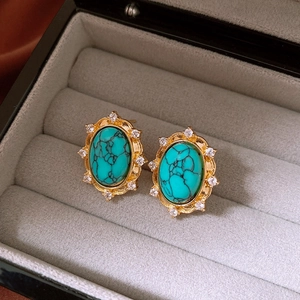 Detailed macro view of vintage turquoise oval stud earring with gold metal and zircon stones