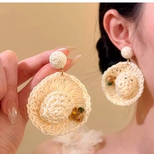 Detailed view of woven raffia hat earrings with floral accents for beach vacations