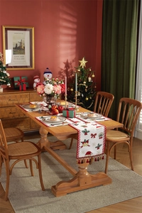Detailed view of red Christmas table runner with tassels and snowflake patterns on wood