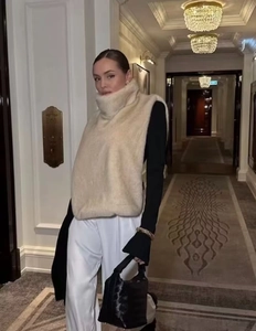 Châle col montant en fausse fourrure beige avec pantalon large blanc et sac à main noir