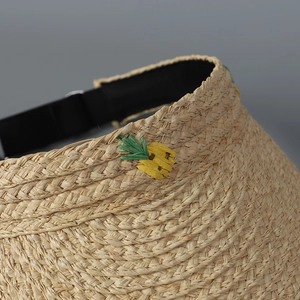 Detail eines Raffia-Sonnenhutes mit gelber Ananas-Stickerei und dichter Webstruktur