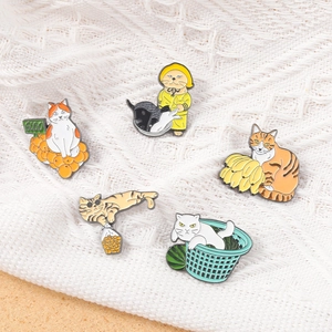 Detailed view of colorful cat enamel pins set featuring fruit and snack themes on fabric