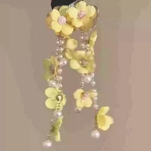 Detail of yellow flower tassel earrings with white pearls on a minimalist background