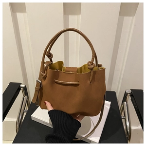 Detail of caramel suede bucket bag showing knotted handle and adjustable side straps