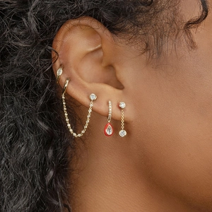 Detailed view of gold chain earrings with zircon studs and red drip oil pendant on model
