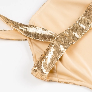 Nahaufnahme der beigen Abendkleid-Träger mit schimmernden Goldpailletten auf Stoff