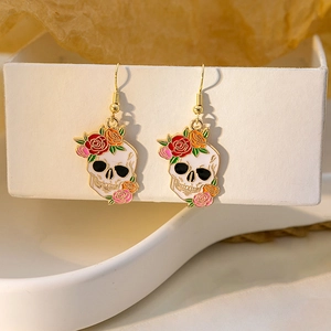 Detail view of skull earrings with colorful roses and gold-tone hooks on white display