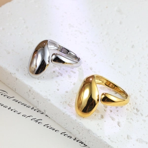 Polished gold and silver stainless steel open rings in teardrop shape on textured stone