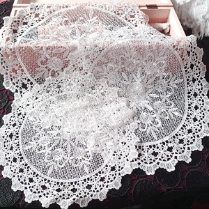 Close-up of intricate white lace embroidery texture on a round hollowed coaster mat