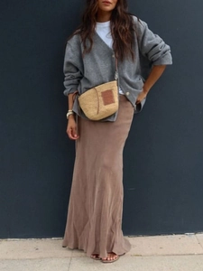 Full shot of gray knitted cardigan paired with a brown maxi skirt and straw bag