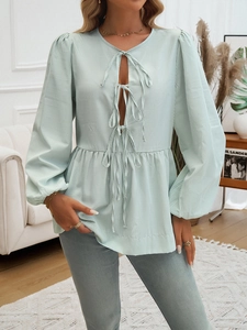 Detail of light green striped blouse featuring a waist tie and pleated hem on female model