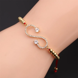 Macro detail of red string bracelet with gold infinity symbol and zircon inlay on wrist