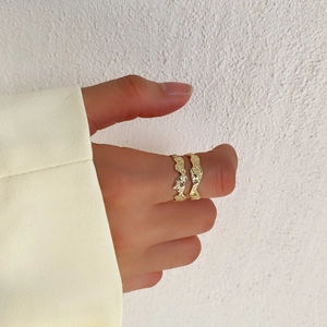 Macro detail of gold irregular molten texture ring worn on a finger for a minimalist look