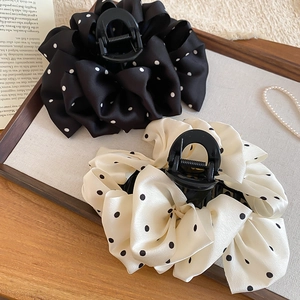Detail of fabric polka dot claw clips with silk texture and large bow design on a tray