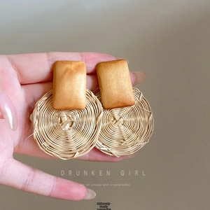 Macro detail of fan-shaped raffia earrings with handmade wood and woven fiber textures