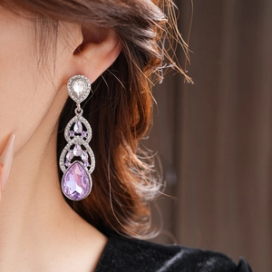 Gros plan d'élégantes boucles d'oreilles goutte en cristal violet portées par un mannequin